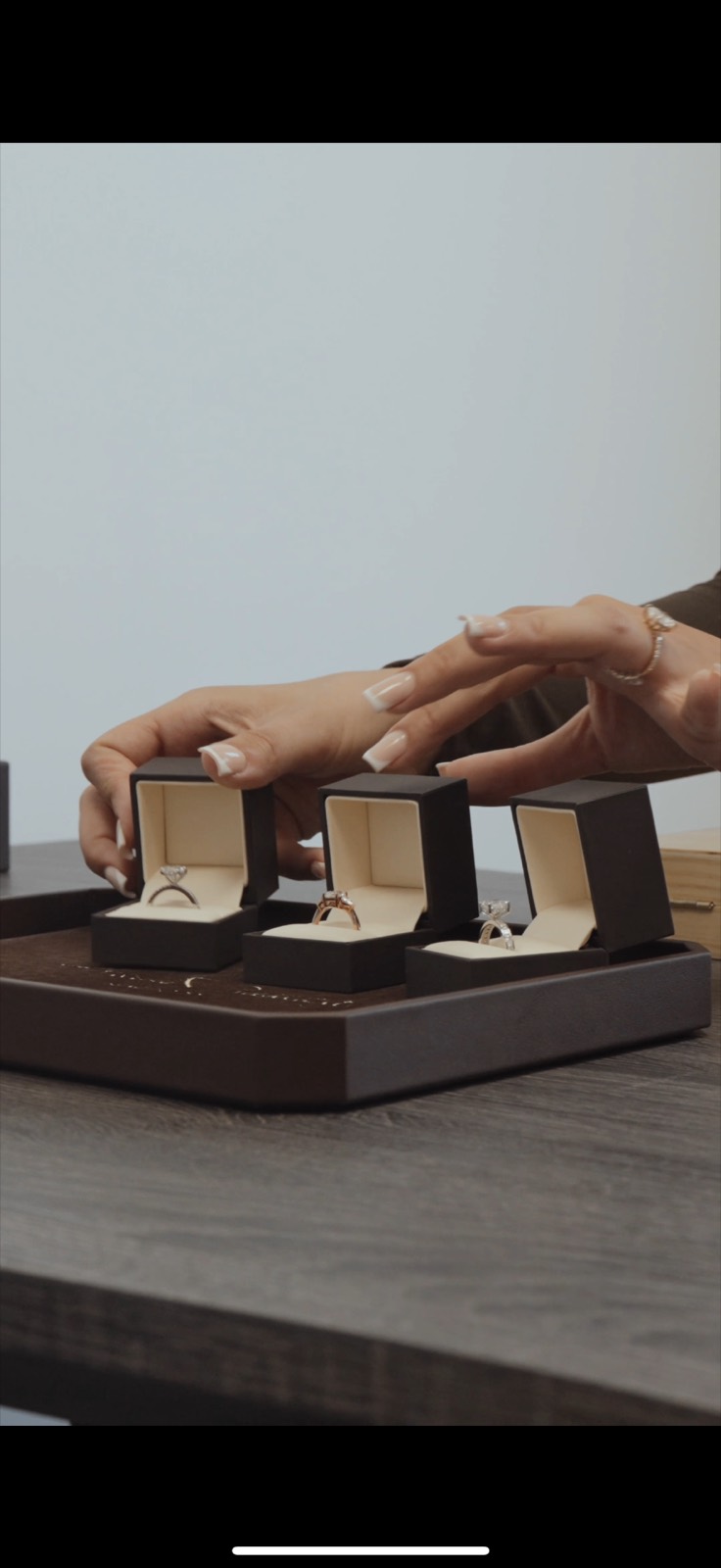 Three engagement rings in presentation boxes on a display tray